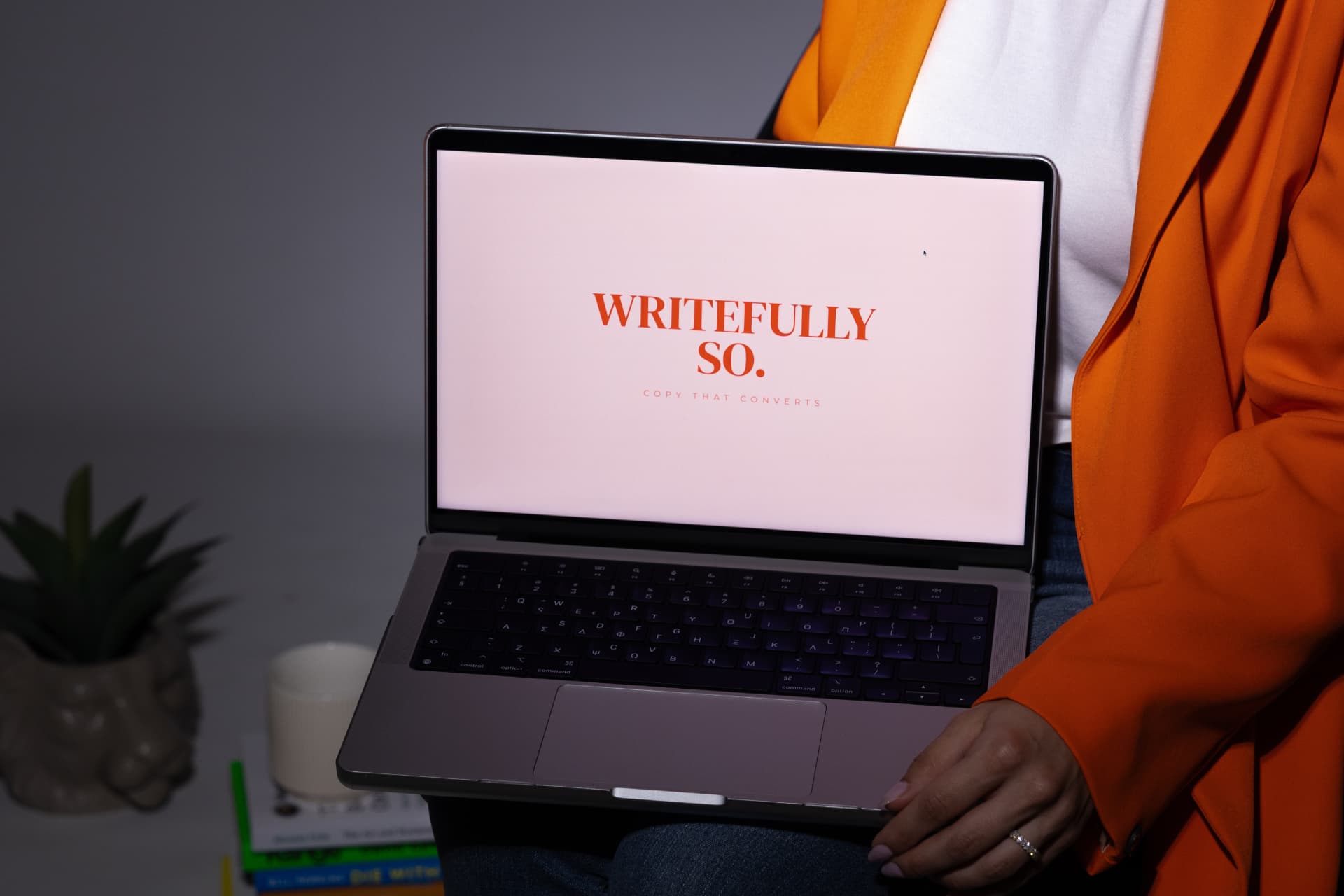 Anna holding a laptop showing the Writefully So logo